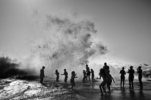Fine art black and white photo of the ocean in Portugal with people enjoying it.