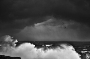 Fine art black and white image of an abstract view of the ocean smashing into a cliff in Portugal