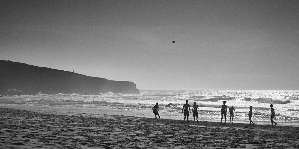 fine art black and white seascape of the atlantic ocean with people in front playing volley