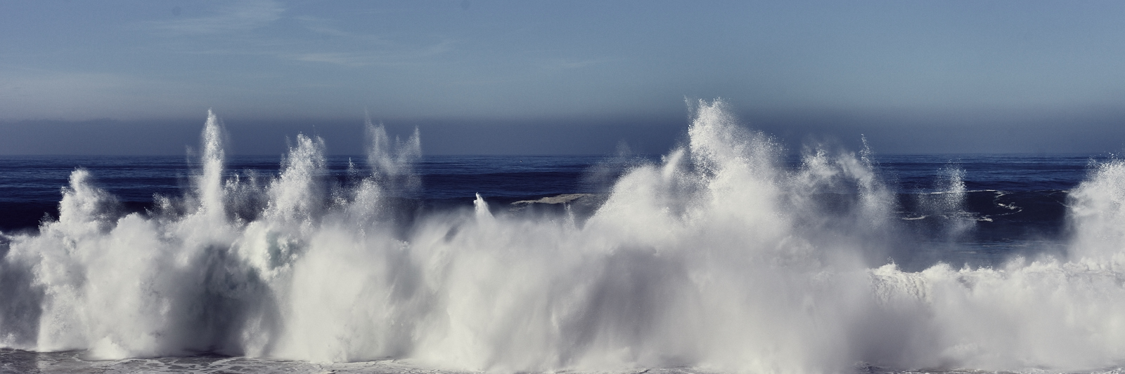 fine art photo of a big wave during a great swell closing in front of a cliff in praia do Malhào 