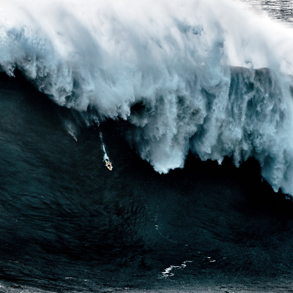 Fine art image of the atlantic ocean showing a surf board getting smashed by a huge wave in NAzaré